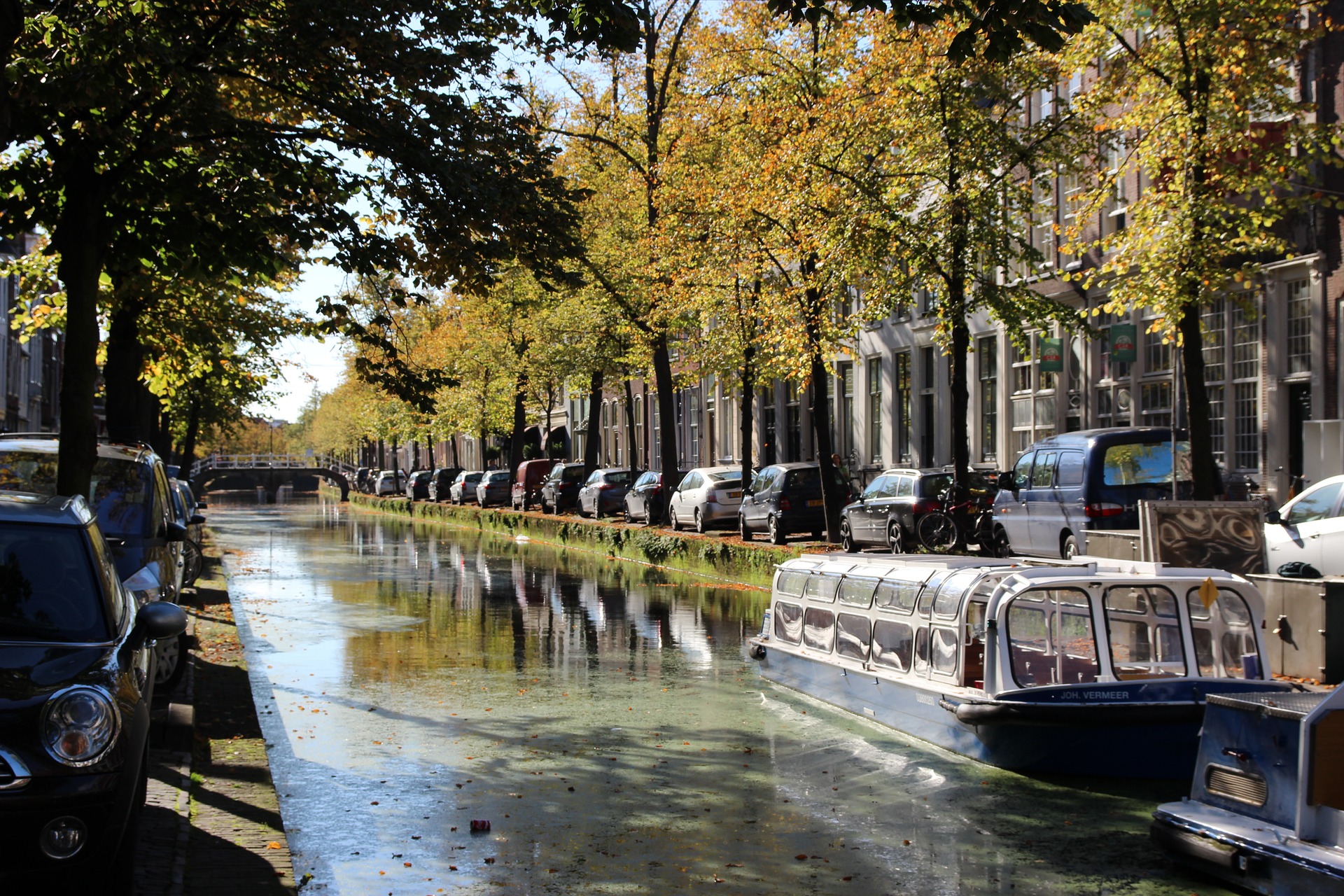 Picturesque canal in Delft, Netherlands with boats and autumn trees